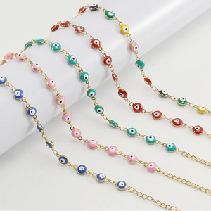 Close-up of five colorful evil eye bracelets in gold plating on white pillars