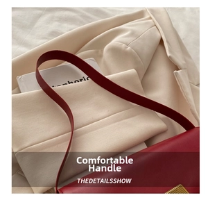 Detail of dark red matte leather bag with golden rectangular lock on beige blazer