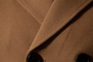Detail of camel wool coat showing twill fabric texture and double-breasted buttons