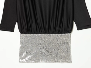 Detail of black draped fabric stitched with dense silver sequins on short dress waist