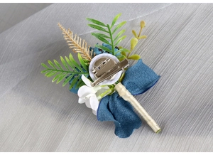 Detail of boutonniere back featuring metal safety pin, clip, and beige ribbon wrap