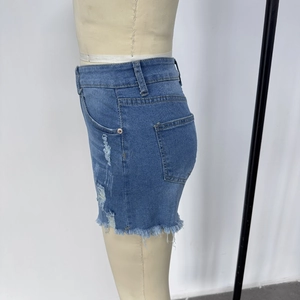 Détail de la mini-jupe en jean taille haute avec déchirures et ourlet effiloché