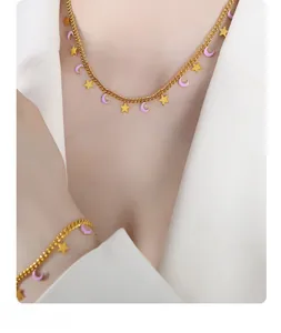 Close-up of vintage gold star and moon necklace with purple enamel on a model