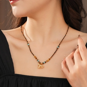 Macro detail of vintage tiger eye beaded necklace with a golden rocking horse pendant