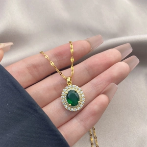Gros plan d'un collier vintage doré avec un grand zircon vert ovale et diamants blancs