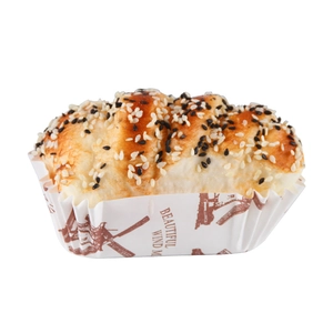 Golden realistic artificial bread prop with sesame seeds on printed parchment paper base