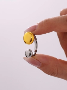 Détail macro d'une bague ouverte minimaliste avec billes contrastées en or et argent