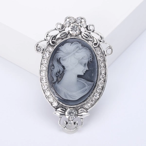 Vintage relief cameo brooch in silver frame with sparkling rhinestones on white background