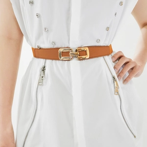 Detail of camel leather elastic waist belt with interlocking gold buckle on white dress