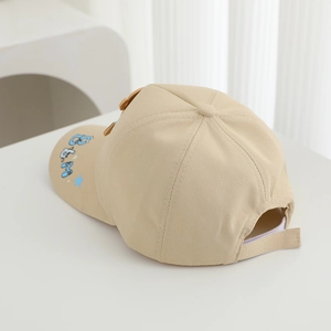 Detail view of beige kids baseball cap with blue embroidery and adjustable strap