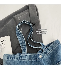Détail des poignées renforcées et du fermoir en métal argenté sur le sac fourre-tout en denim