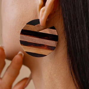Close-up of geometric striped wooden earrings worn by a model in a fashion style