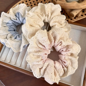 Detail of sweet floral lace scrunchies in pastel blue, beige, and pink fabric textures