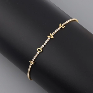 Close-up of gold LOVE letter necklace with zircon pavé on a professional black display