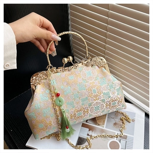 Detail of vintage embroidered handbag with gold metal frame, floral pattern and green tassel