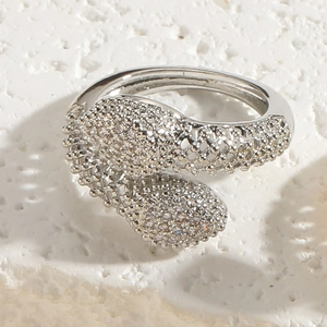 Detailed top view of snake-shaped silver ring with pave-set zircon stones on stone surface