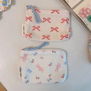 Detail of pink floral cotton mini coin purses with zipper and brand label on desk