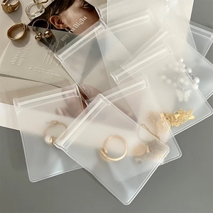 Detailed view of frosted transparent jewelry storage bags on a textured grey surface