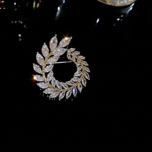 Elegant silver leaf wreath brooch with marquise cut zircon crystals on a black reflective surface