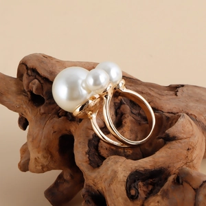 Detailed view of gold metal ring with two white pearls on a natural wood surface