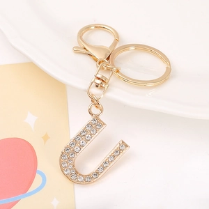 Macro view of gold-plated metal letter U keychain encrusted with clear rhinestones
