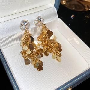 Macro detail of gold-tone tassel earrings with zircons in a jewelry box