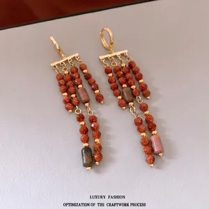 Boucles d'oreilles vintage à pompons dorés avec perles de grès orange sur fond gris