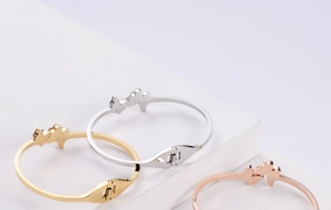Detailed macro view of three butterfly bangles in gold, silver and rose gold finishes