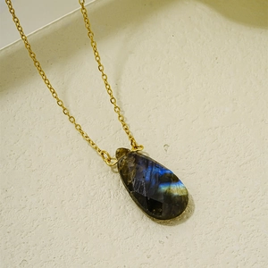 Gros plan d'un pendentif en labradorite naturelle en forme de goutte avec collier doré