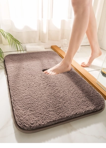 Close-up of soft brown microfiber bath mat with anti-slip texture on marble bathroom floor