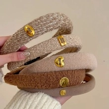 Detailed close-up of earth-toned tweed headbands featuring golden decorative buckles