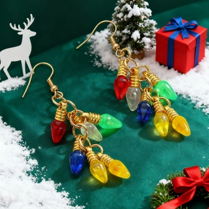 Détail de boucles d'oreilles de Noël avec mini ampoules colorées sur soie verte