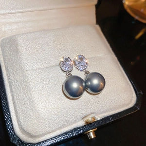 Gros plan d'une boucle d'oreille en perle grise et cristaux dans un écrin en velours