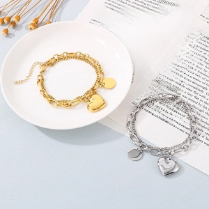 Detail view of double-layered heart and disk pendants on gold and silver bracelets