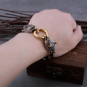 Détail du bracelet tête de loup viking bicolore argent et or sur le poignet d'un homme