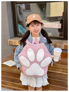 Close-up of pink cute cat paw backpack with white padded details on a little girl