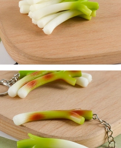 Detailed view of miniature green onion keychain with realistic texture on a wooden board