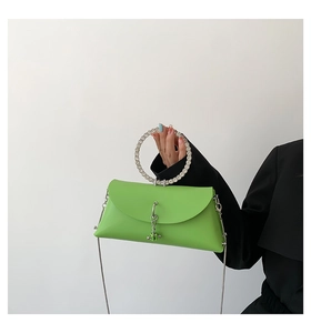 Detail of a bright green jelly bag with a crystal-encrusted ring handle and chain