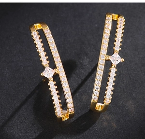 Détail de boucles d'oreilles doubles dorées avec pavé de zircons et une grande pierre carrée