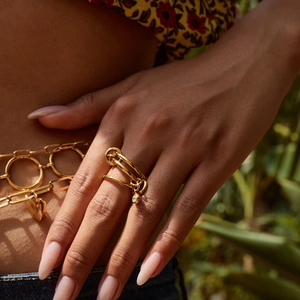 Detail of layered gold titanium steel ring with sparkling zircon pendant on model hand