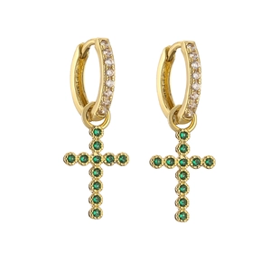 Detailed shot of golden hoop earrings with cross pendants and emerald green gemstones