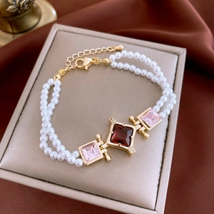 Détail d'un bracelet de perles double couche avec zircons carrés rouges et roses dorés