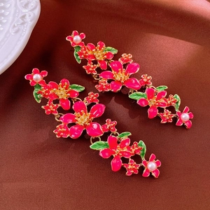 Detail of pink enamel flower earrings with green leaves and white pearls on gold base