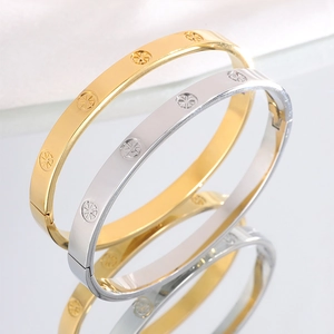 Detail view of gold and silver luxury steel bracelets with gear-pattern engraving