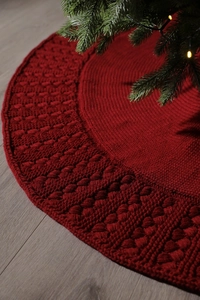 Close-up of red knitted Christmas tree skirt with detailed hollow weave texture