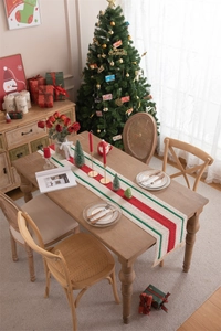 Detail of cotton linen Christmas table runner with festive tassels and striped pattern