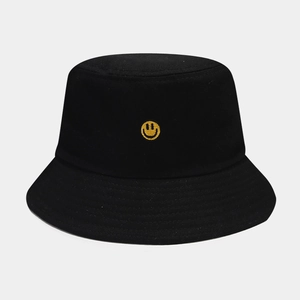 Close-up of the yellow smiley face embroidery on a black cotton canvas bucket hat