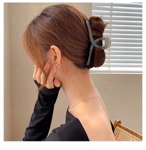 Detail of a large smoky gray shark hair claw clip used in a stylish hair twist hairstyle