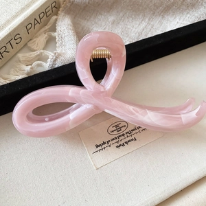 Close-up of pink marble texture hair claw clip with golden spring and elegant design