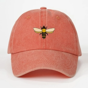 Close-up of embroidered bee on washed orange cotton baseball cap with vintage texture